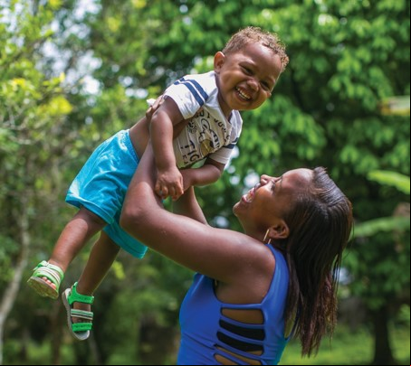 Mãe segura bebê no alto, ambos sorriem