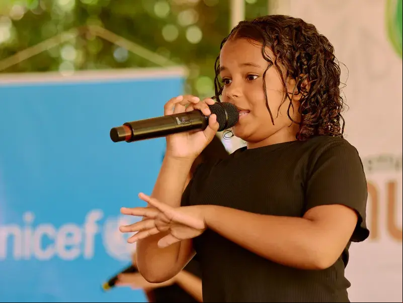 A frente do banner azul do UNICEF, adolescente do NUCA se expressa