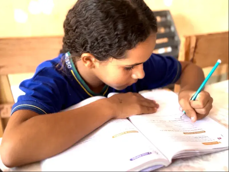 Adolescente negra fardada escrevendo em um livro