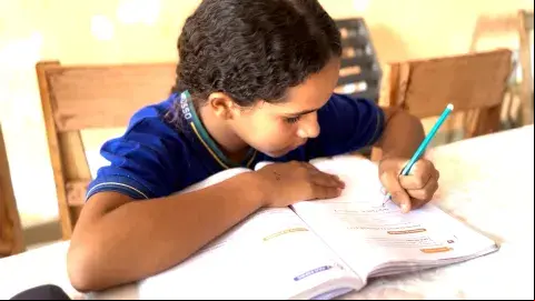 Adolescente negra fardada escrevendo em um livro